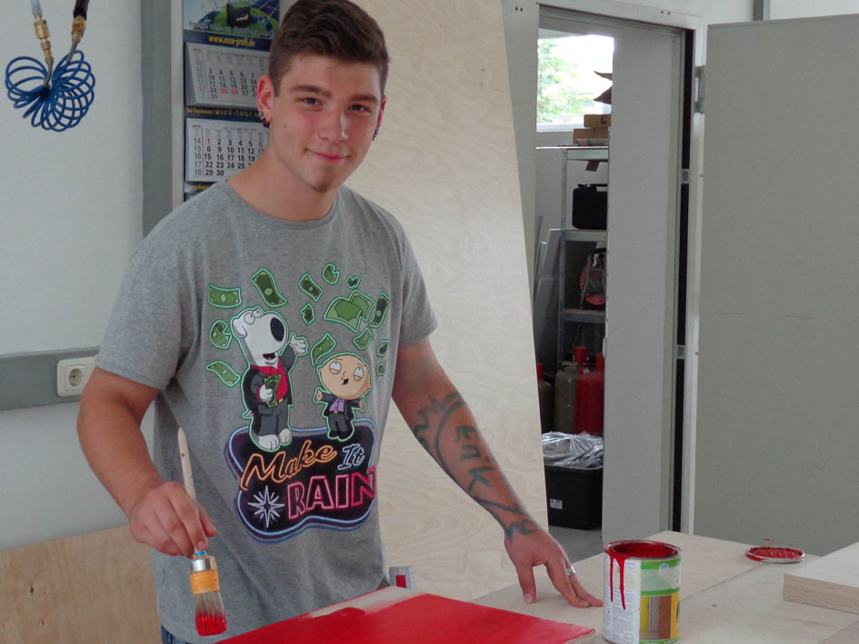 Mann trägt ein schlichtes graues T-Shirt und hat die Hände in den Taschen.