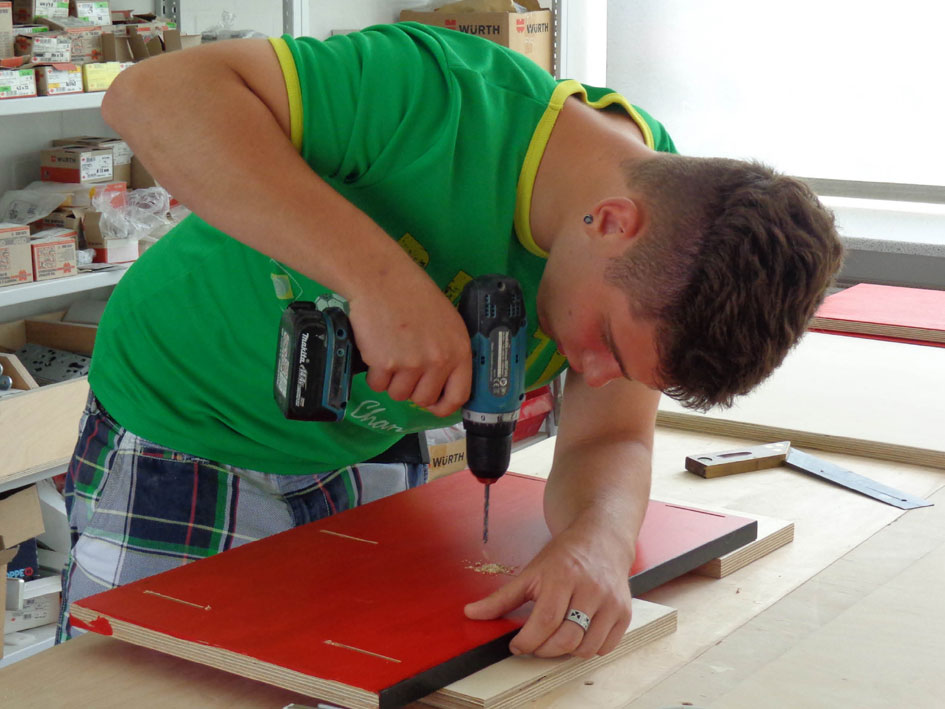 Ein Mann benutzt eine Bohrmaschine, um ein Loch in ein Stück Holz zu bohren.