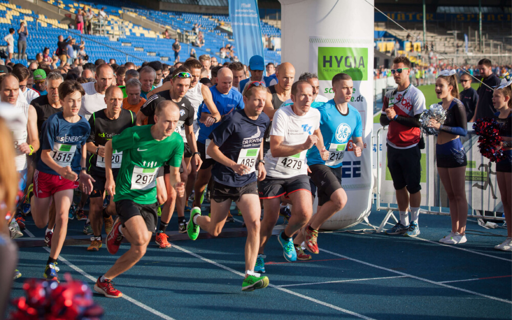 Startschuss für einen Marathon: Viele Läufer beim Stadtlauf im Stadion, Sportveranstaltung mit Zuschauern und Cheerleadern.