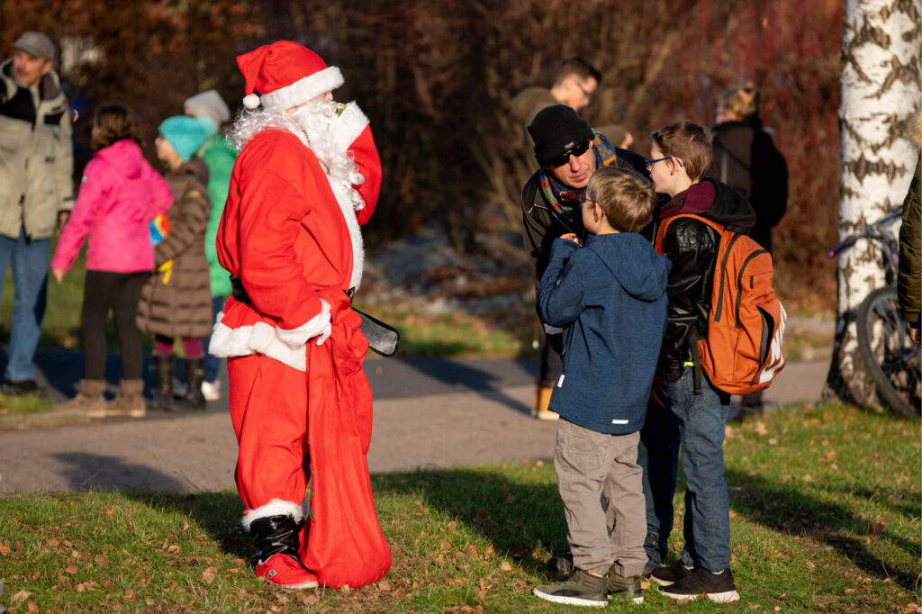 Weihnachtsmann im Park mit Kindern. Nikolaus verteilt Geschenke, Weihnachtszeit, Adventszeit, festliche Stimmung, Weihnachtsmarkt.