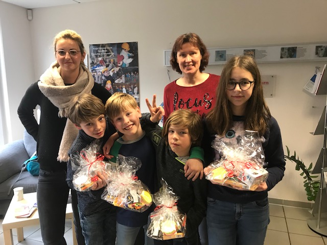 Gruppe von Kindern und Frauen hält Geschenke, möglicherweise für eine Wohltätigkeitsorganisation oder Spendenaktion.