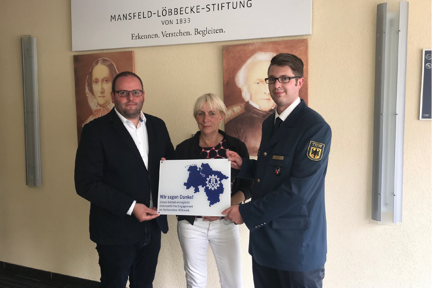 Mansfeld-Löbbecke-Stiftung: Dank für ehrenamtliches Engagement im Technischen Hilfswerk (THW). Ehrenamtliche Helfer mit Schild.