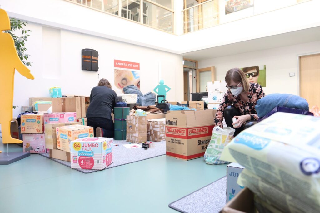 Spendenaktion: Helfer packen Hilfsgüter in Kartons. Windeln, Kleidung und mehr für Bedürftige. Ehrenamtliche Hilfe, soziales Engagement.