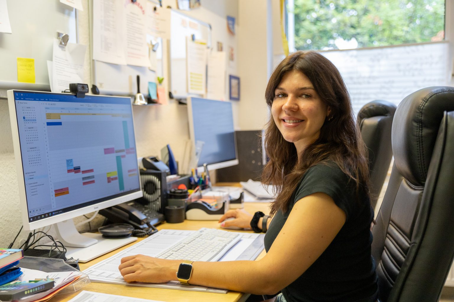 Frau arbeitet am Schreibtisch mit Computer, Kalender und Büromaterial. Büroorganisation und Terminplanung im Büroalltag.