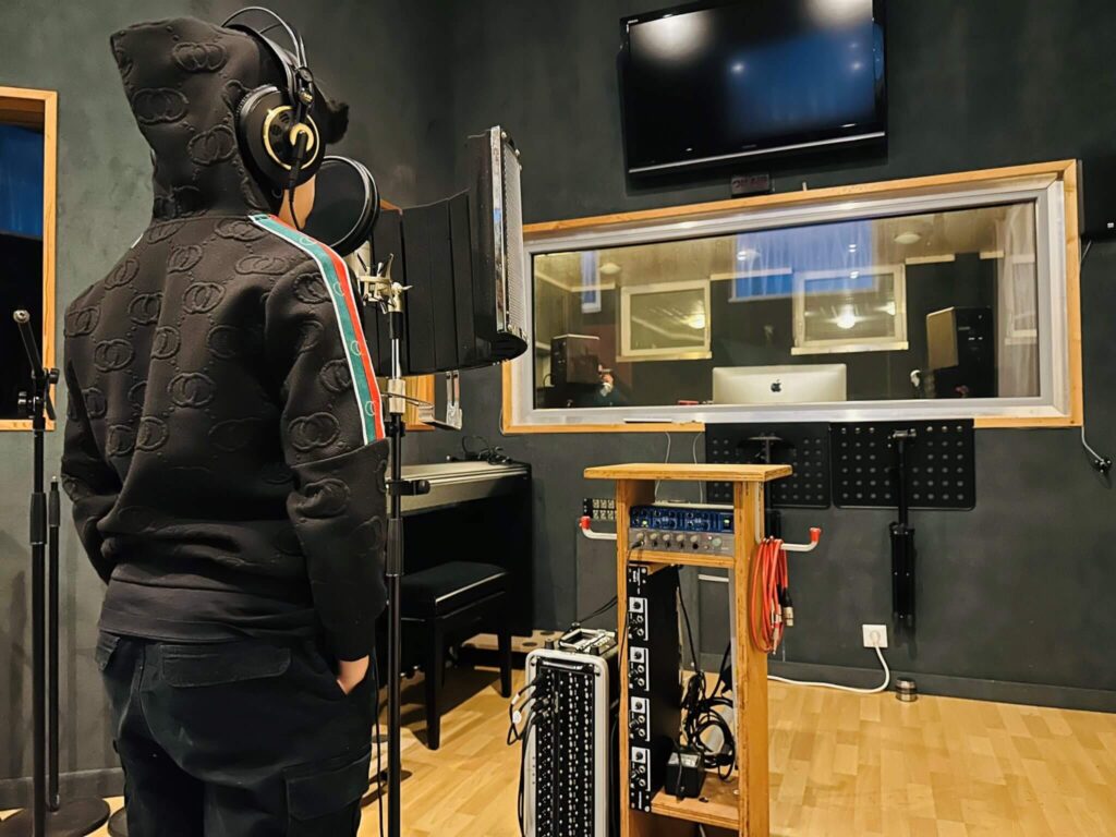 Ein Mann in einem Tonstudio trägt Kopfhörer und konzentriert sich auf die Aufnahme.