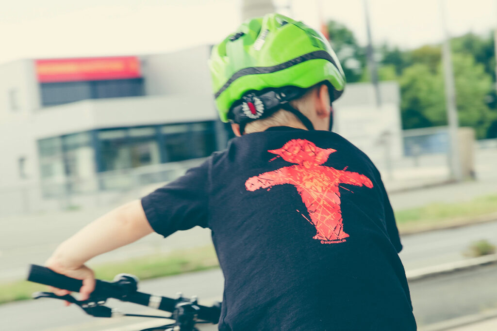 Ein Kind mit Helm fährt fröhlich auf einem Fahrrad.