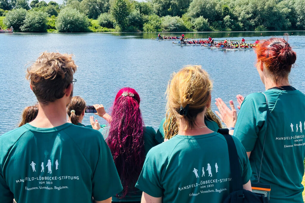 Eine Gruppe von Menschen in grünen T-Shirts steht am Ufer eines Sees.