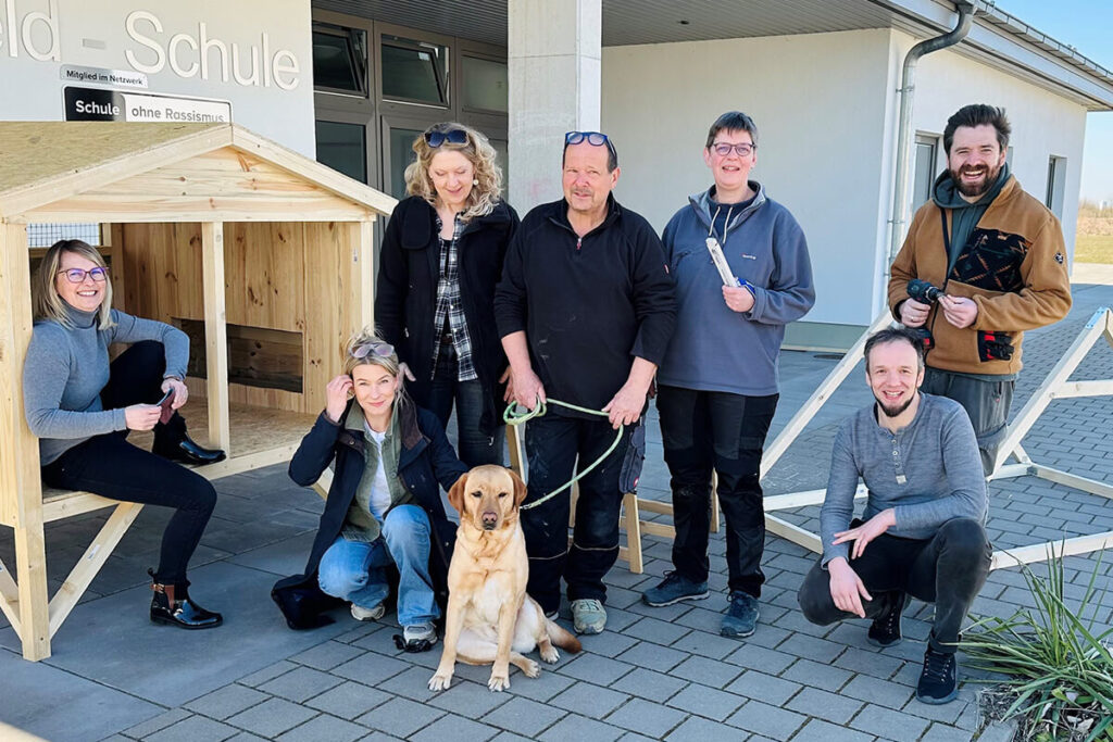 Ehrenamtliche Helfer bauen ein Hundehaus für die Grundschule Feld-Schule. Teamwork mit Hund für ein soziales Projekt in der Gemeinde.