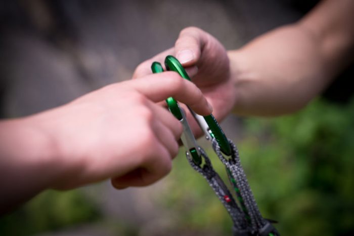 Eine Person hält ein grünes und schwarzes Kletterseil in der Hand.