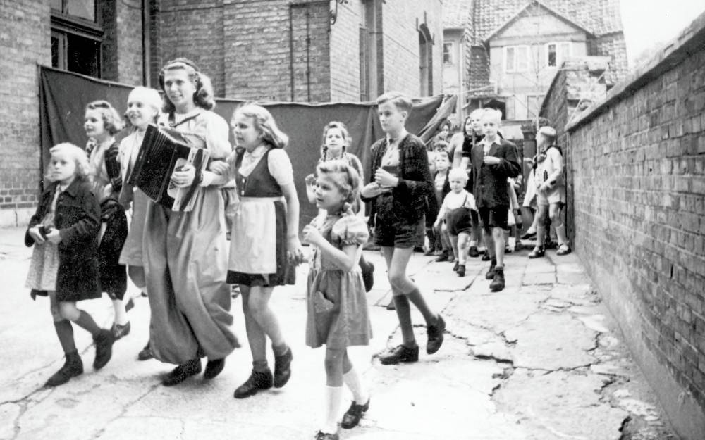 Kinder laufen gemeinsam auf einer belebten Straße.