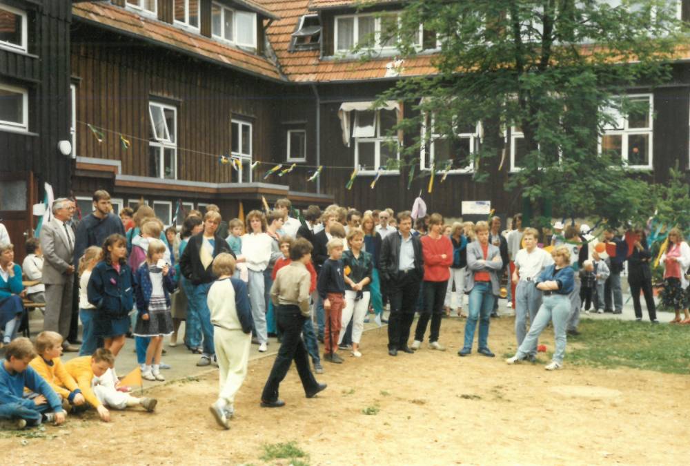 Eine Gruppe von Menschen versammelt sich um ein Gebäude und diskutiert lebhaft.