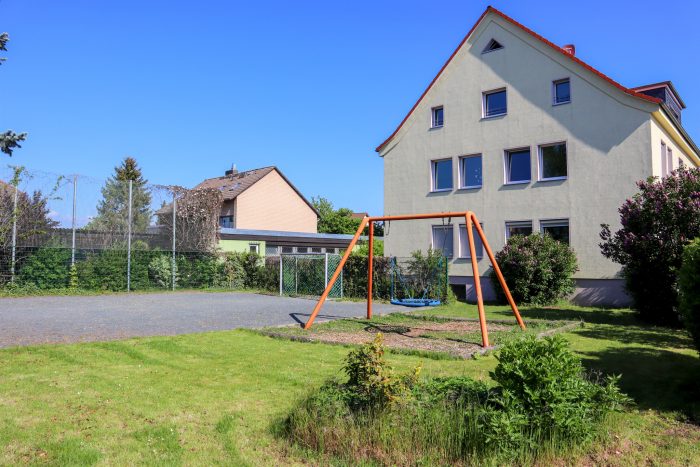 Ein Haus mit einer Schaukel im Garten.