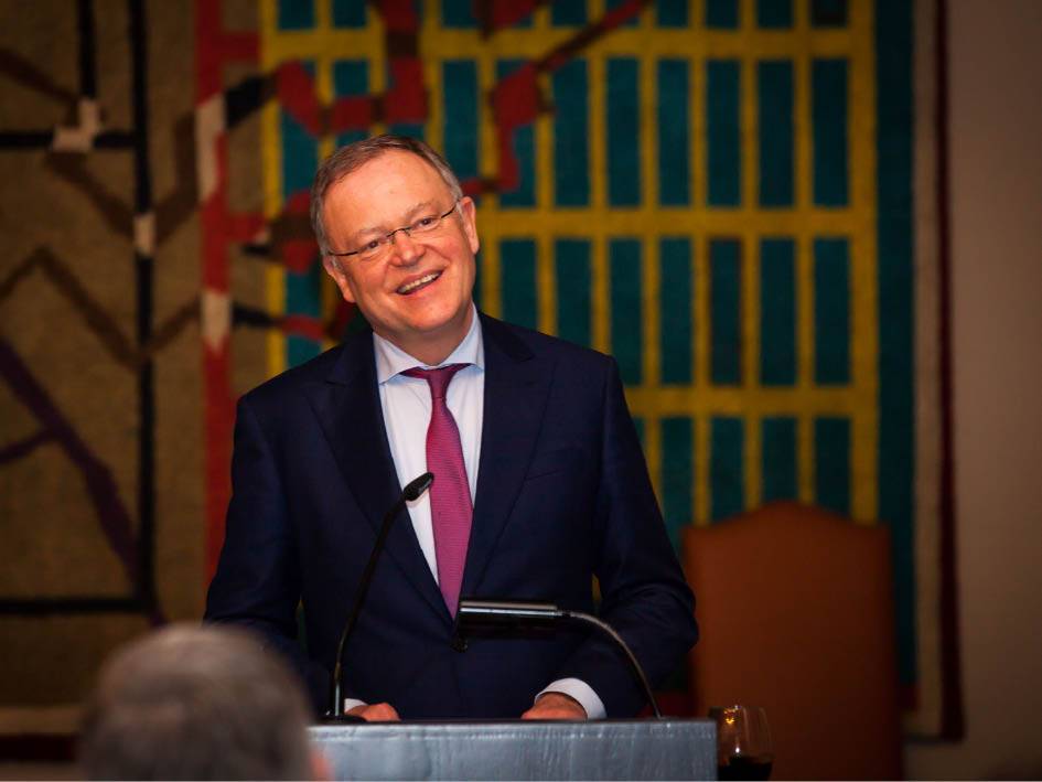Ein Mann in formeller Kleidung steht an einem Podium und hält eine Rede.