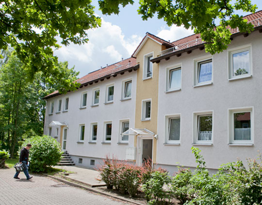 Ein Mann geht auf einem Bürgersteig vor einem Gebäude entlang.