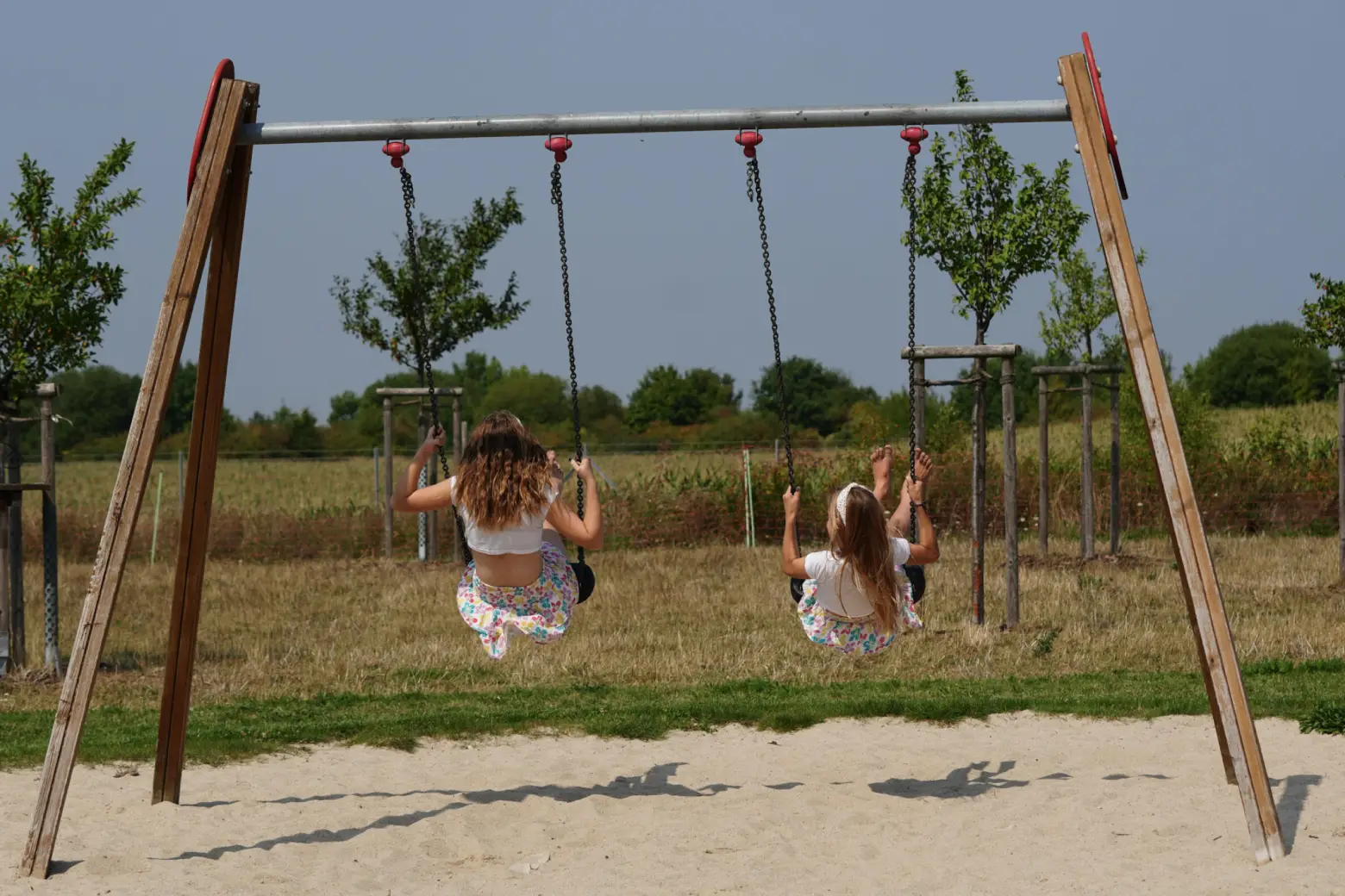 wei Mädchen schaukeln gemeinsam auf einem Spielplatz im Freien